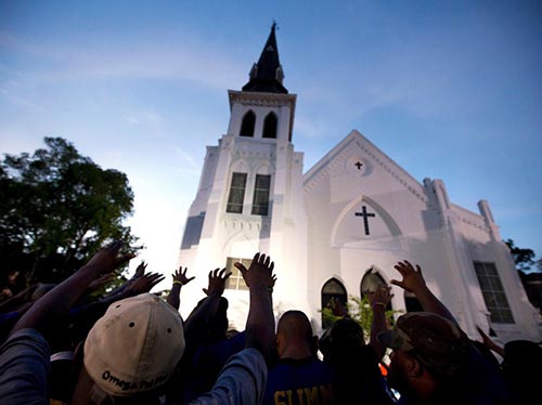 The men of Omega Psi Phi Fraternity Inc. lead a crowd of people in prayer outside the Emanuel AME Church.