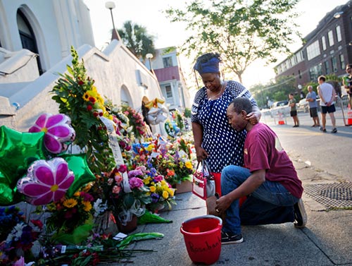 Allen Sanders, right, kneels next to his wife Georgette as they pray at a sidewalk memorial in front of Emanuel AME.